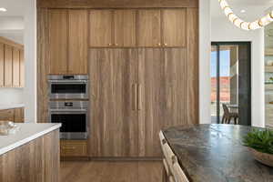 Kitchen with wood finish cabinets, recessed lighting, dark wood-type flooring, stainless steel double oven, and light countertops