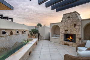 Patio terrace at dusk featuring an outdoor stone fireplace and a patio