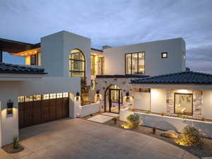 View of front of house with stone siding, concrete driveway, a garage, stucco siding, and a tiled roof