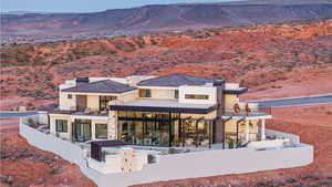Back of property featuring a patio area, a mountain view, a balcony, stucco siding, and stone siding