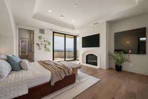 Bedroom with wood finished floors, access to exterior, recessed lighting, and a glass covered fireplace