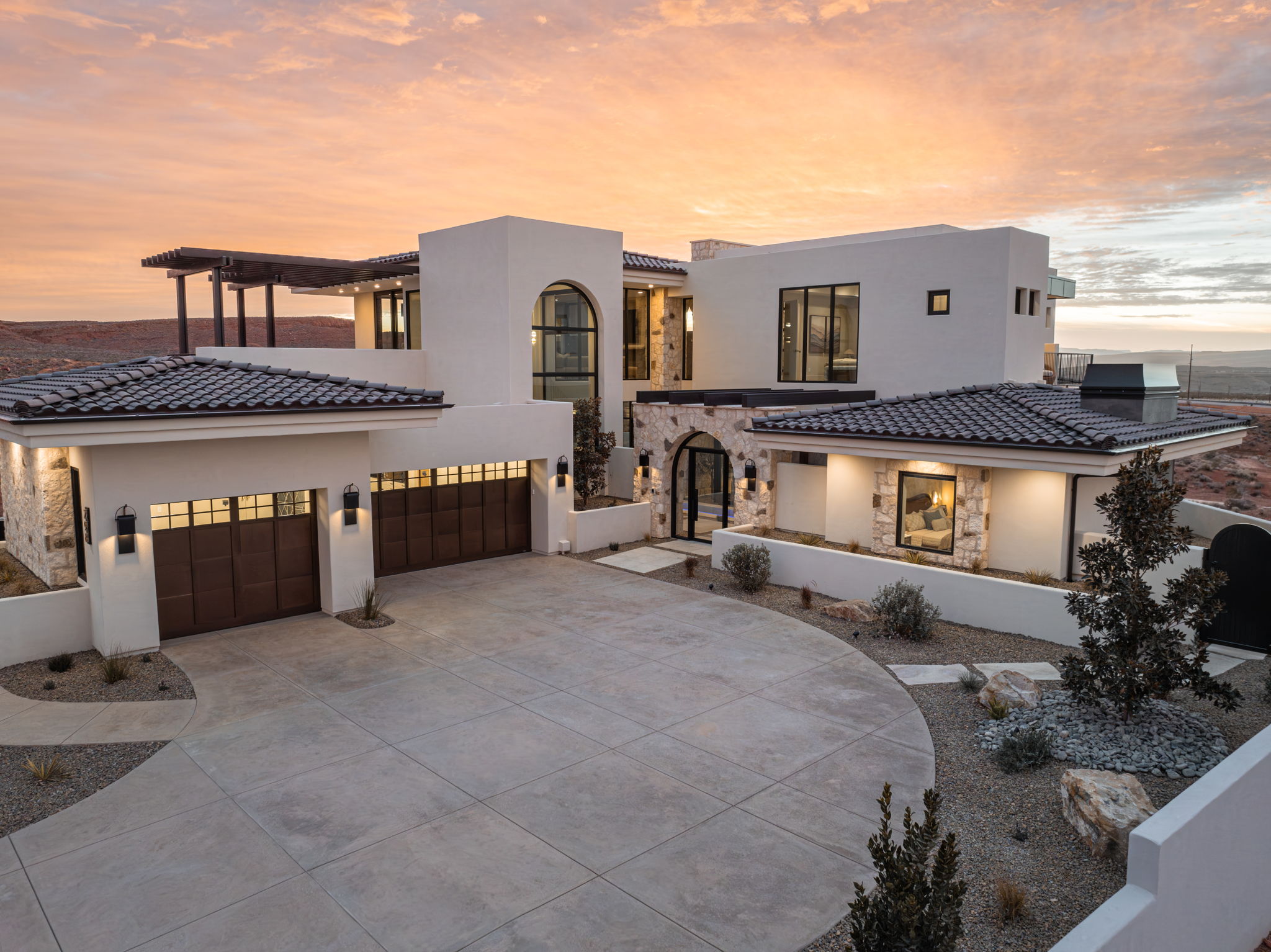 View of front facade featuring stone siding, stucco siding, driveway, and an attached garage