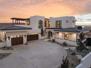 View of front facade featuring stone siding, stucco siding, driveway, and an attached garage