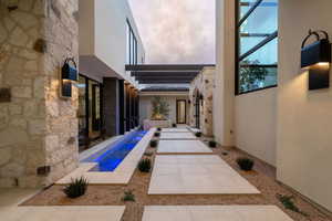 Rear view of property featuring stone siding, stucco siding, a patio area, and an outdoor pool