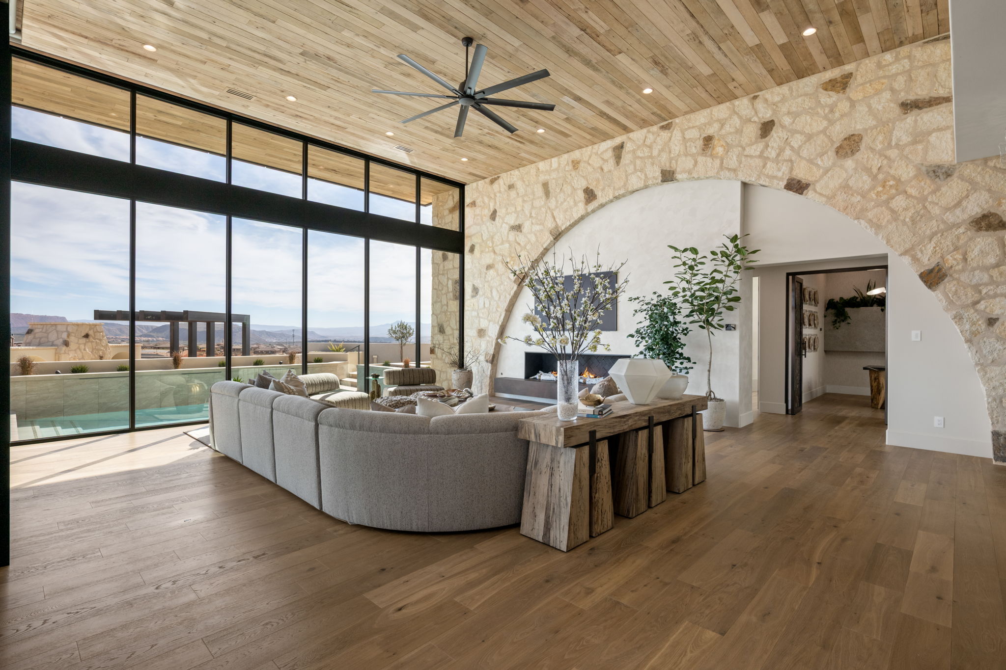 Living area featuring a high wood ceiling, floor to ceiling windows, hardwood / wood-style floors, ceiling fan, and a warm lit fireplace