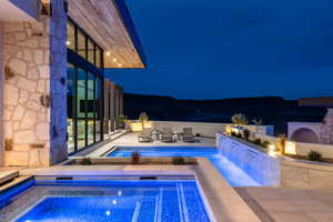Pool at night with an outdoor pool, a patio area, and an in-ground hot tub