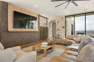 Living area with arched walkways, wood finished floors, ceiling fan, recessed lighting, and expansive windows