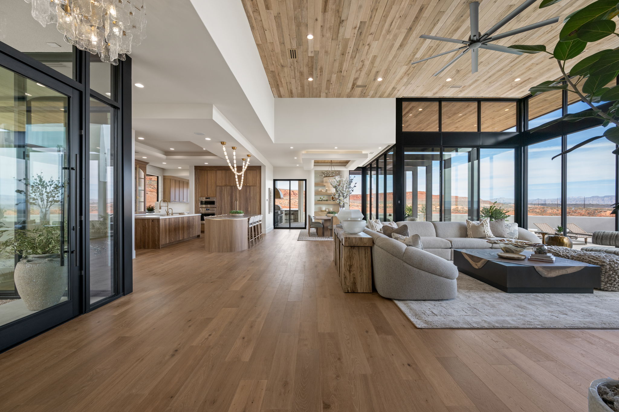 Living area featuring hanging lights, light wood-style flooring, ceiling fan, and a wooden tray ceiling