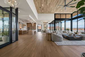 Living area featuring hanging lights, light wood-style flooring, ceiling fan, and a wooden tray ceiling