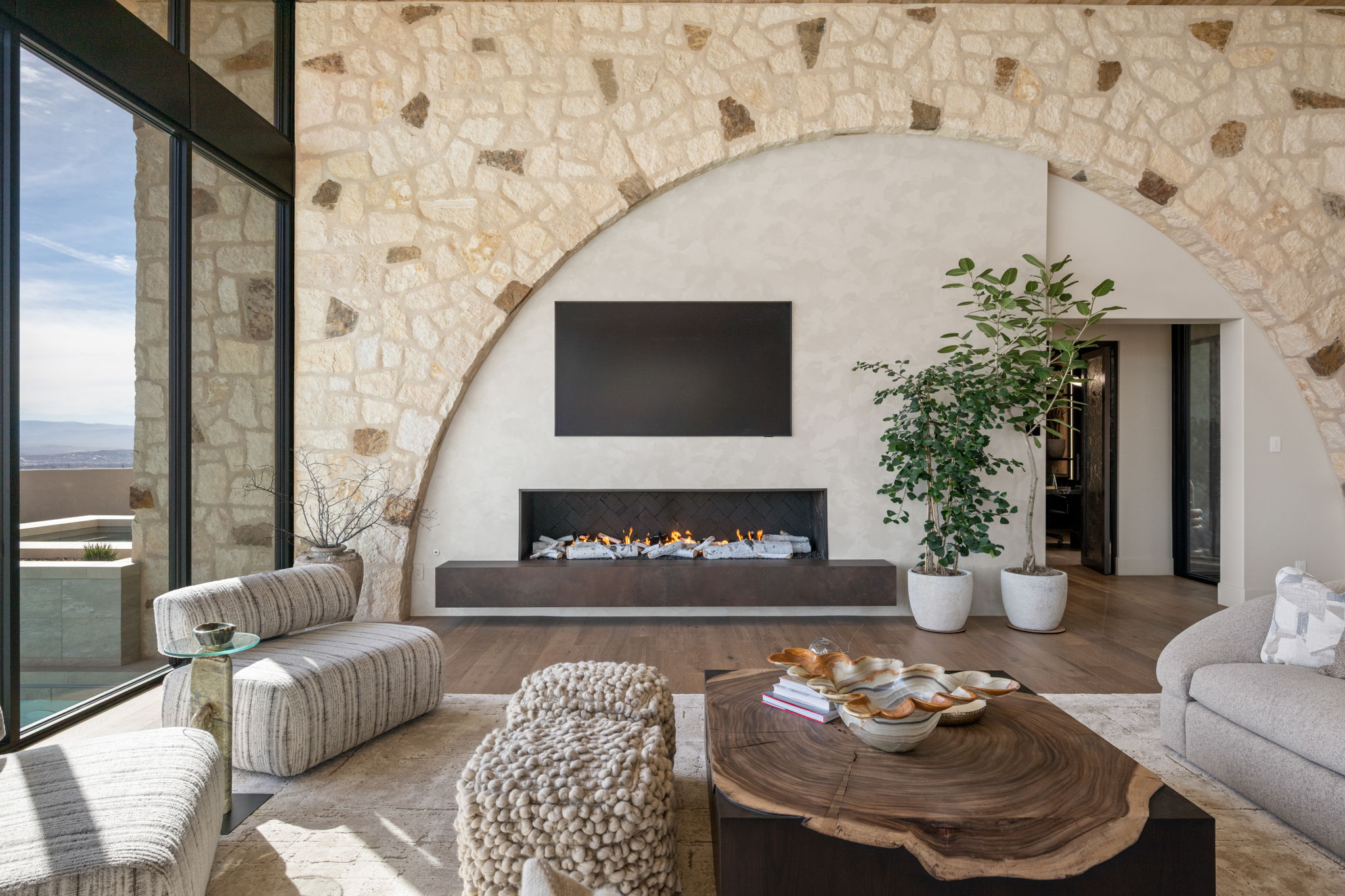 Living room featuring wood finished floors, a warm lit fireplace, and arched walkways