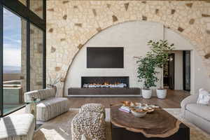 Living room featuring wood finished floors, a warm lit fireplace, and arched walkways