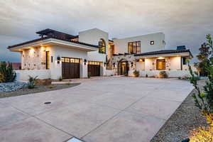 View of front facade with stone siding, concrete driveway, stucco siding, and an attached garage