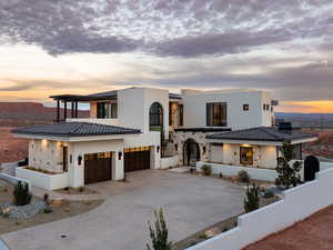 View of front of property featuring stone siding, concrete driveway, stucco siding, and a tiled roof