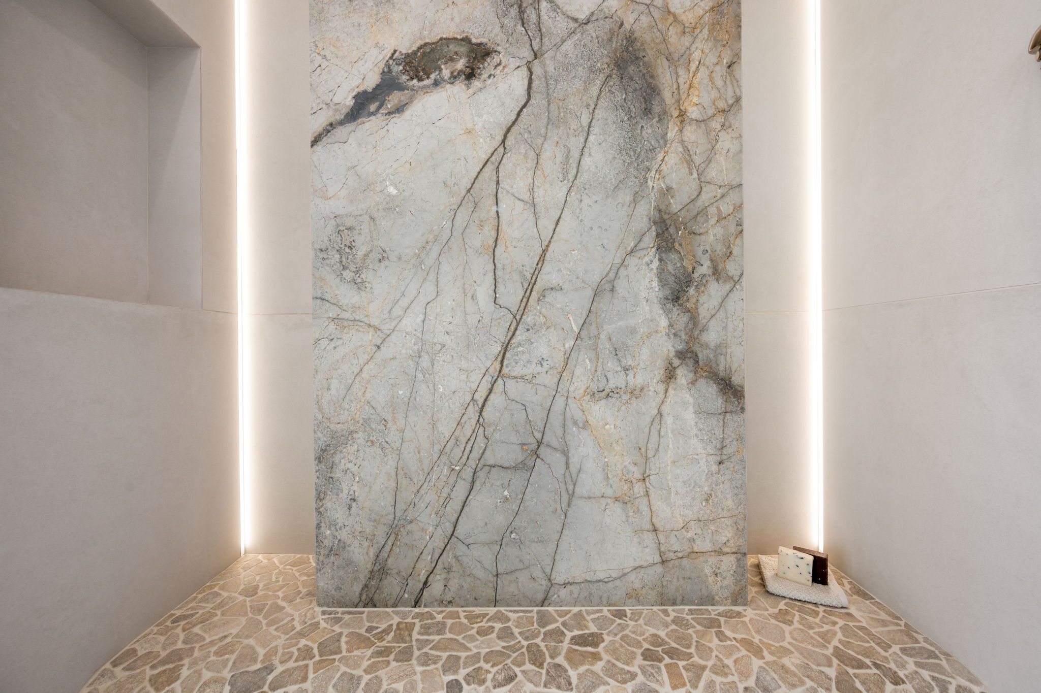 Full bathroom with stone flooring and a marble finish shower