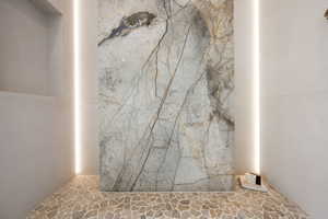 Full bathroom with stone flooring and a marble finish shower