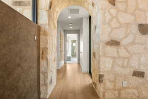 Hallway featuring arched walkways, light wood-type flooring, and recessed lighting