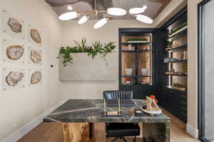Office space featuring light wood-type flooring, hanging lights, and built in shelves
