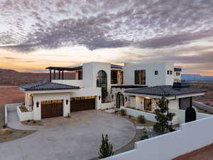 View of front facade featuring stucco siding, concrete driveway, a mountain view, a garage, and stone siding