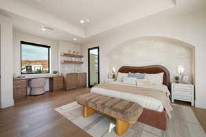 Bedroom featuring built in study area, wood-type flooring, a tray ceiling, and recessed lighting