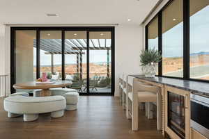 Dining space with a mountain view, beverage cooler, dark wood finished floors, expansive windows, and recessed lighting