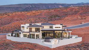 Rear view of property with a mountain view, a balcony, a patio, stucco siding, and a chimney