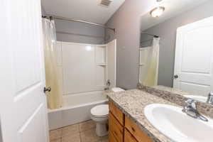 Bathroom with vanity, shower / bath combo, a textured ceiling, and light tile patterned floors