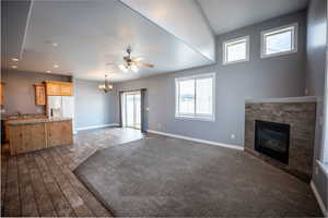 Unfurnished living room featuring a chandelier, a glass covered fireplace, a ceiling fan, and wood finish floors