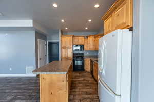 Kitchen with black appliances, a center island, recessed lighting, wood tiled floors, and light wood finish cabinetry