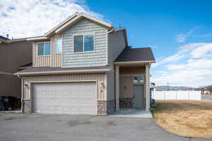 View of front of property with a garage, a shingled roof, asphalt driveway, and board and batten siding
