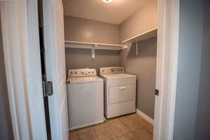 Laundry room featuring light tile patterned floors and washer and clothes dryer