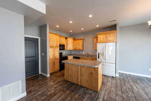 Kitchen with black appliances, a center island, wood tiled floors, recessed lighting, and light wood finish cabinetry