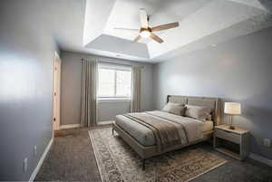 Bedroom with carpet floors, a ceiling fan, and a tray ceiling