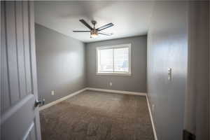 Carpeted spare room featuring baseboards and a ceiling fan
