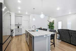 Kitchen with gray cabinetry, stainless steel appliances, a kitchen bar, and open floor plan