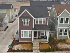 Traditional-style house featuring board and batten siding, concrete driveway, a porch, a residential view, and roof with shingles