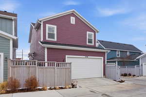 View of front of house with a garage, concrete driveway, and a gate