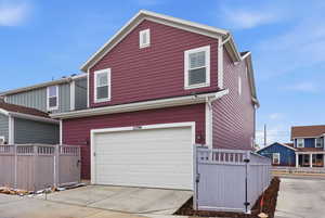 View of property exterior featuring a gate, an attached garage, and concrete driveway