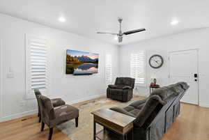 Living area with a ceiling fan, light wood finished floors, and recessed lighting