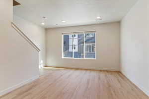Unfurnished living room with light wood finished floors, a textured ceiling, and recessed lighting