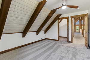 Additional living space with lofted ceiling with beams, light colored carpet, a ceiling fan, and wood ceiling
