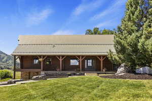 Cabin featuring a metal roof, a front lawn, and covered porch