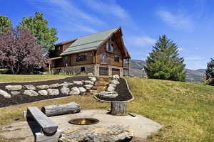 Rear view of property with a fire pit, log exterior, a yard, an attached garage, and a mountain view