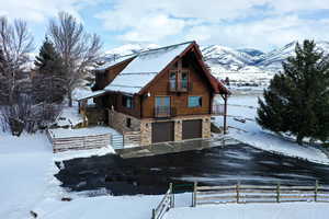 View of front of house with an attached garage, stone siding, and log exterior