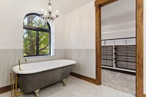 Bathroom with a wainscoted wall, a freestanding bath, and suspended lighting