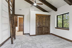 Carpeted bedroom with a ceiling fan, a high wood beamed ceiling, and a closet