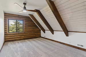 Bonus room featuring log walls, carpet, vaulted ceiling with beams, a ceiling fan, and wood ceiling