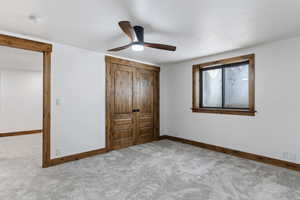 Unfurnished bedroom featuring carpet, ceiling fan, and a closet