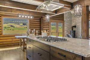 Kitchen with log walls, french doors, dark wood finish cabinetry, light wood finished floors, and decorative light fixtures