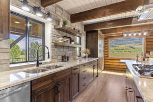 Kitchen with open shelves, light stone countertops, stainless steel appliances, light wood-type flooring, and rustic walls