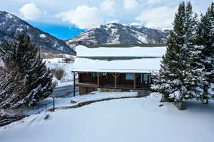 View of front of house with covered porch, a mountain view, faux log siding, and stone siding